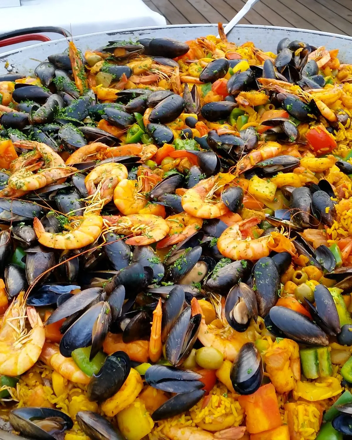 A large pan of freshly made seafood paella served outdoors