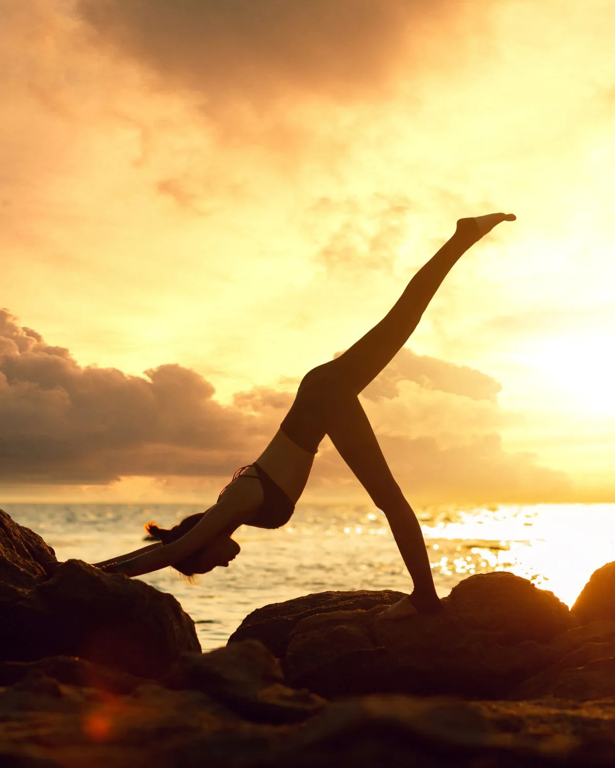 Yoga at sunset on the rocks by the Mediterranean