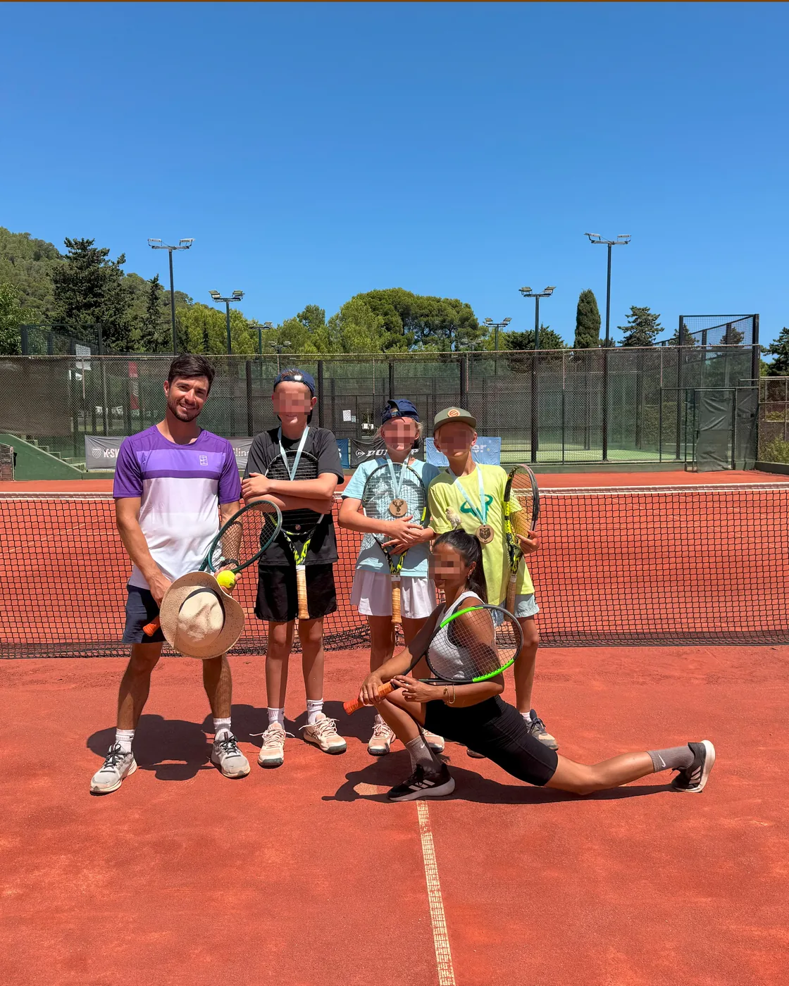 Coach and junior players on a clay court